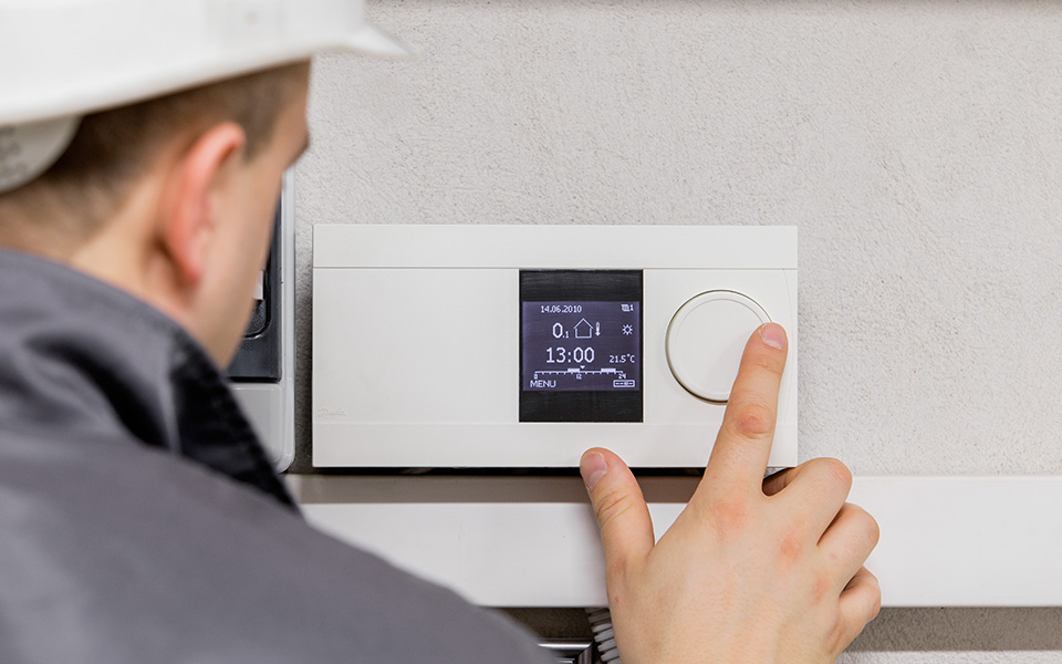 man operating a thermostat on the wall